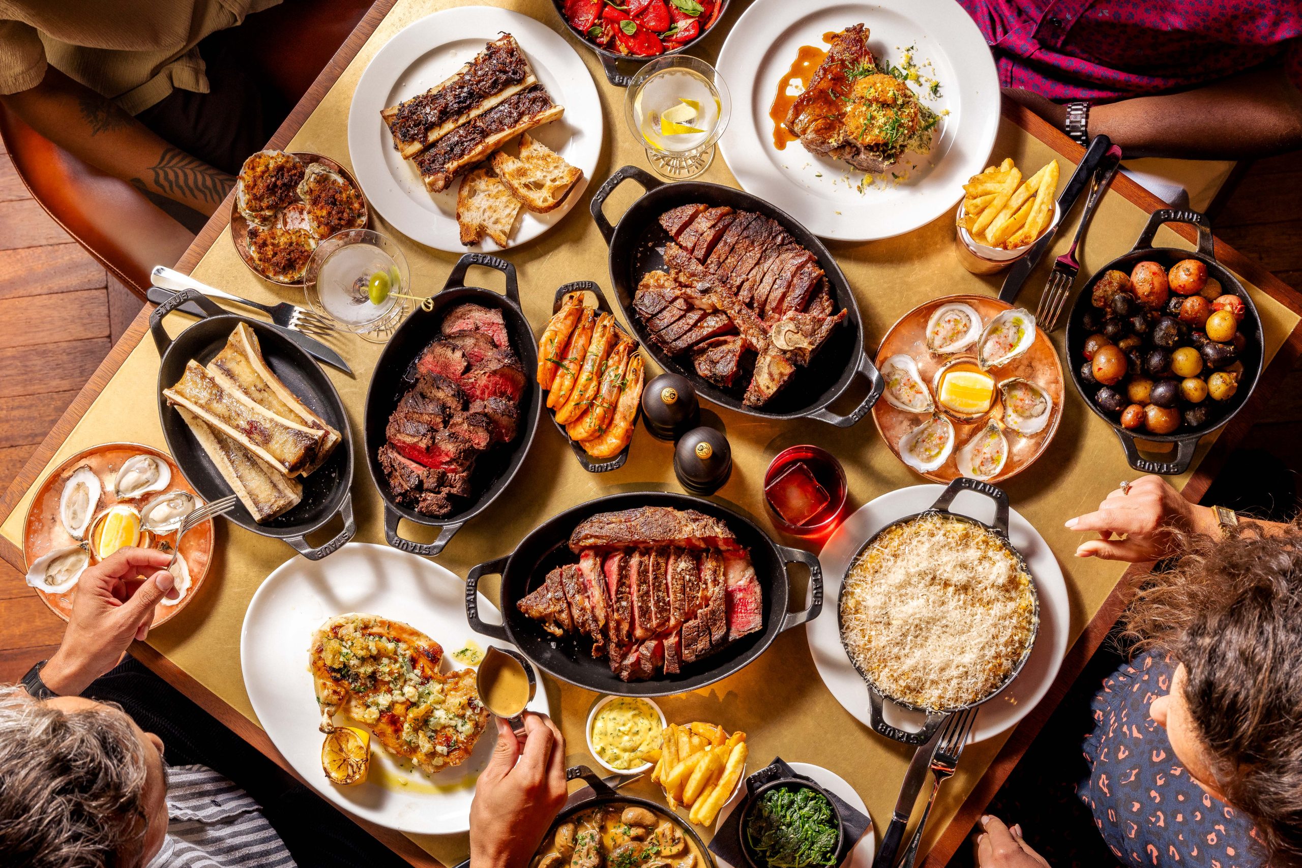 An overhead shot of a table generously laden with steaks, seafood and sides