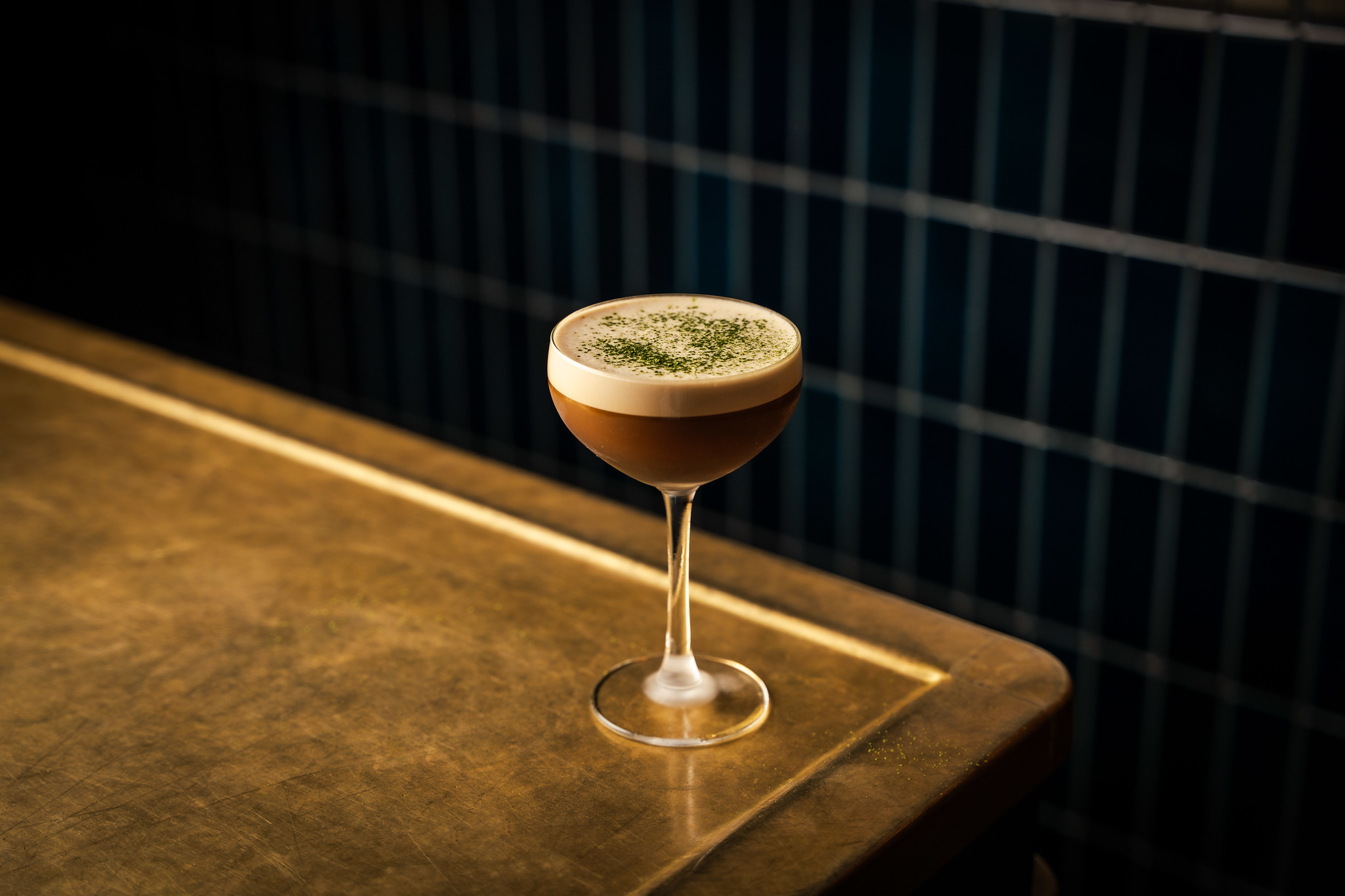 Espresso martini cocktail shot in a moody style, on the edge of a golden table