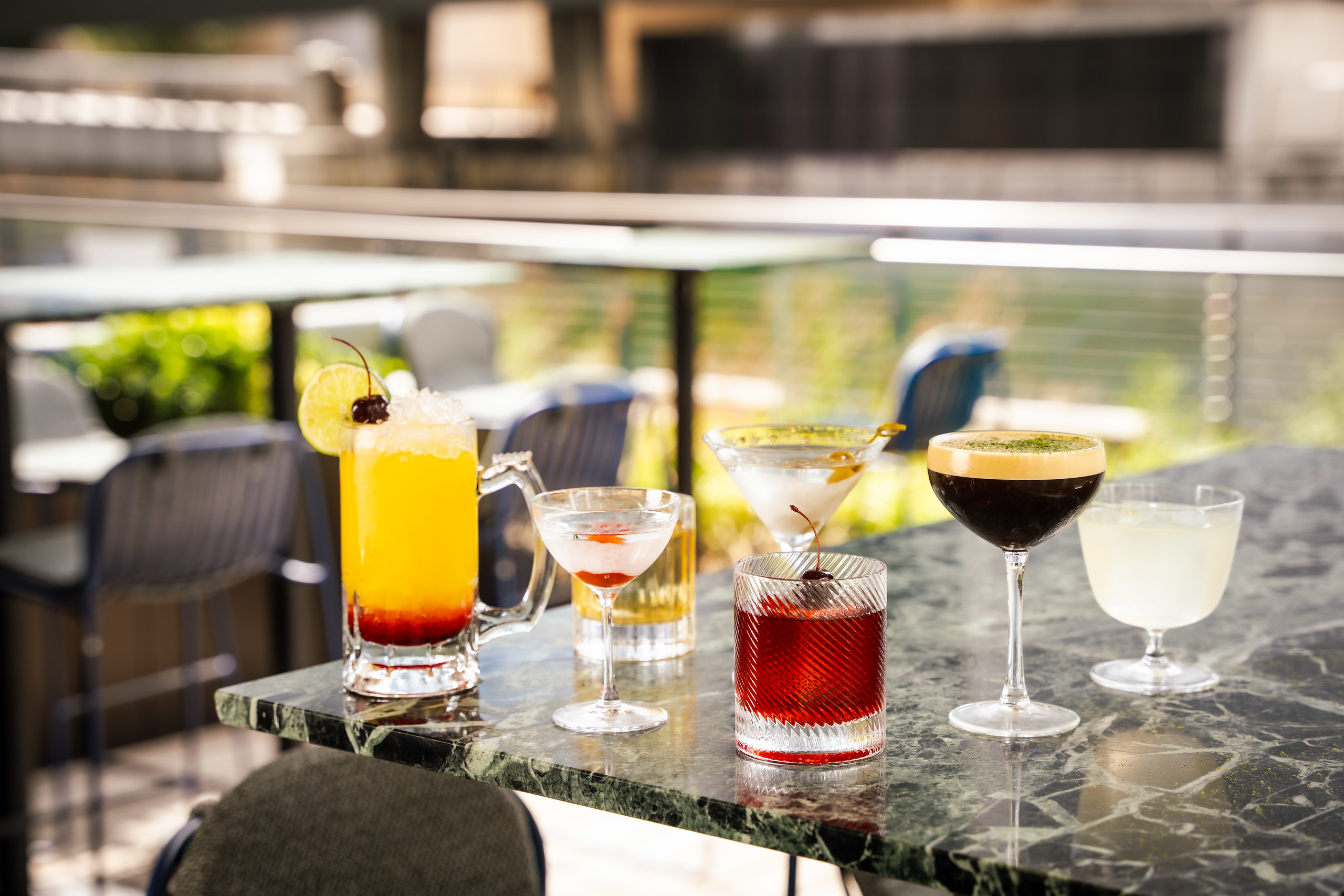 A collection of Hawksmoor cocktails shot outside, on a marble table