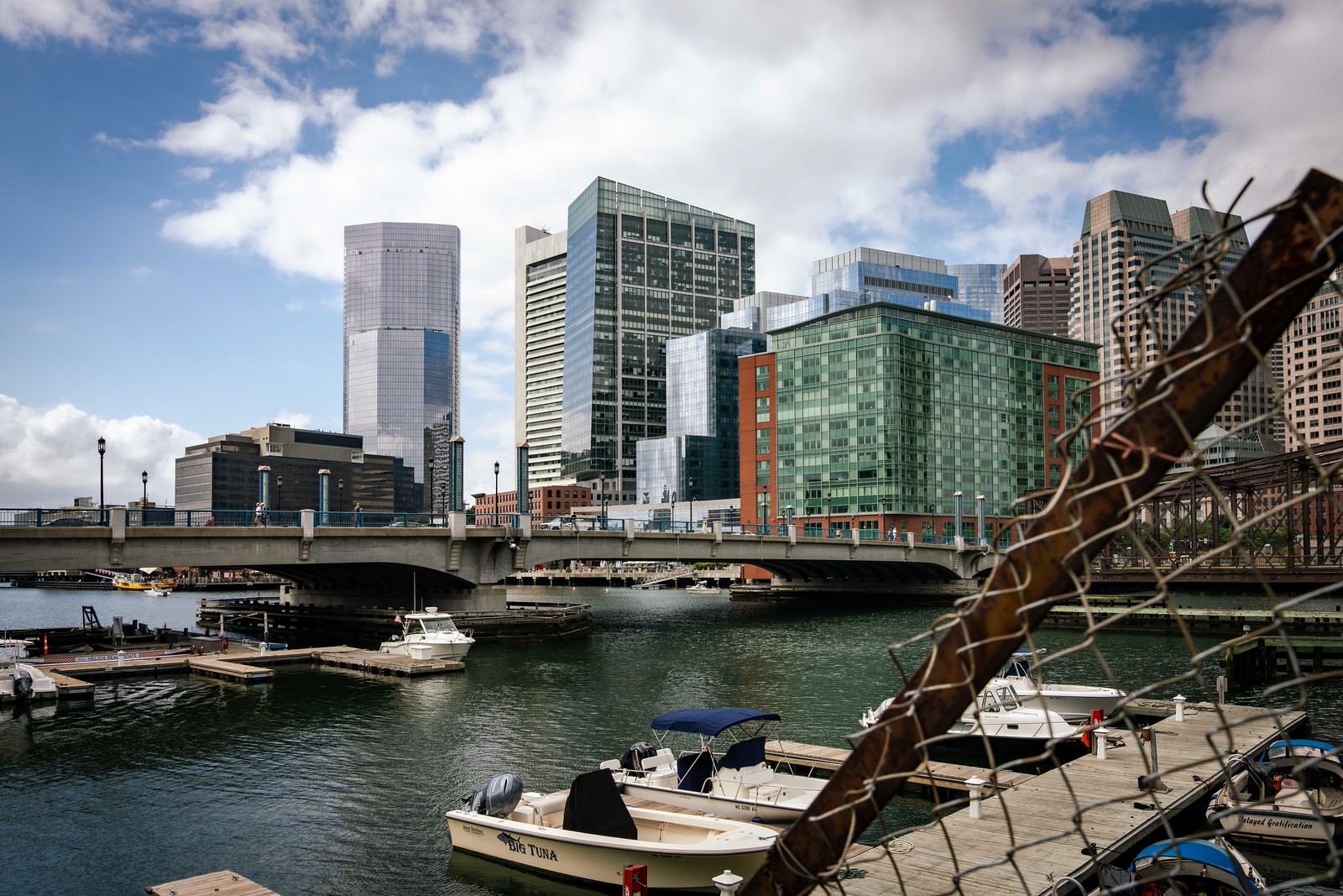 A wide shot of Boston panorama from the wharf, with skyscrapers at the back and some boats at the front in the marina