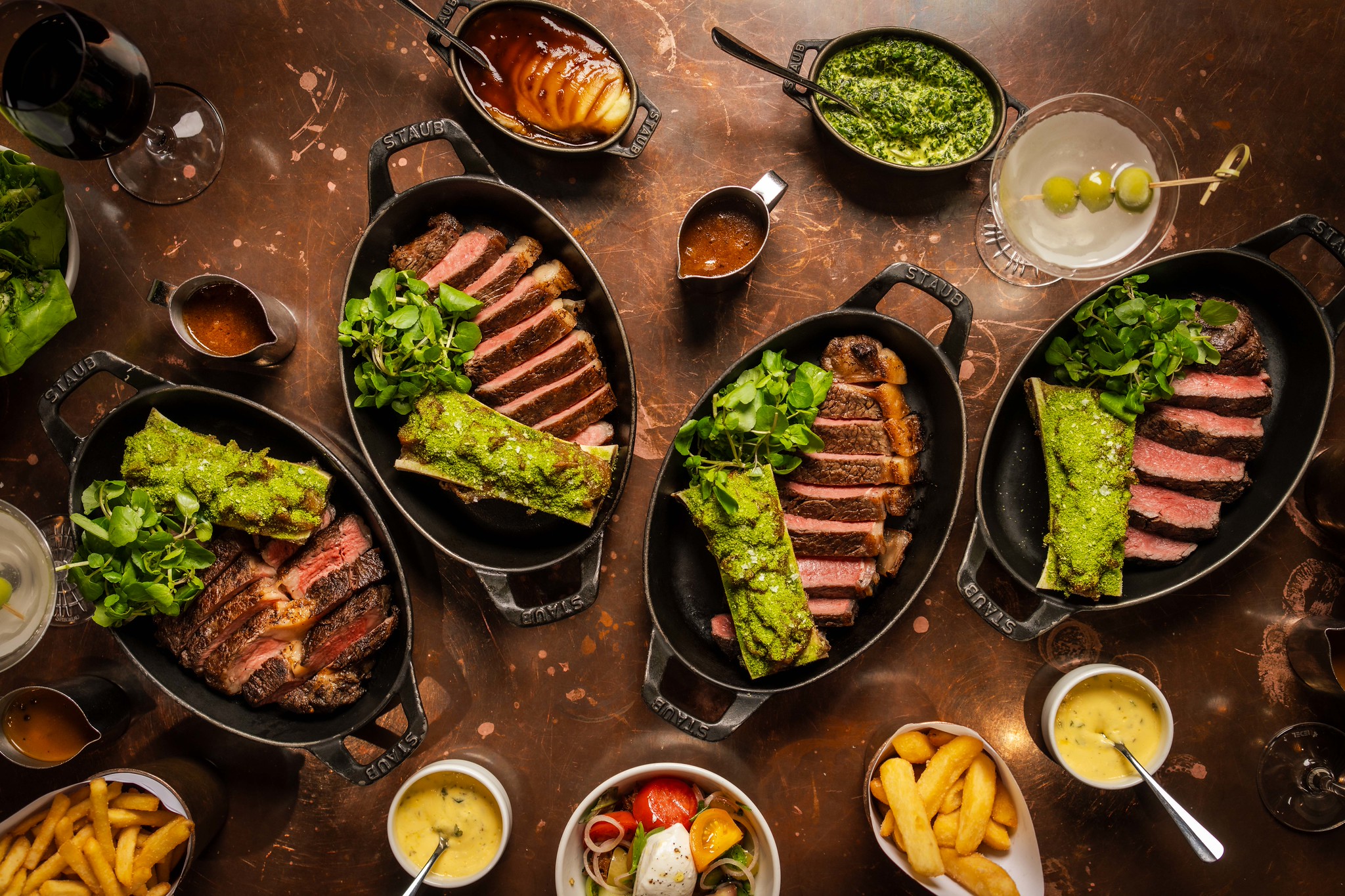 The Hawksmoor steak flight served in four cast iron dishes, with chips, sauces and sides across the table