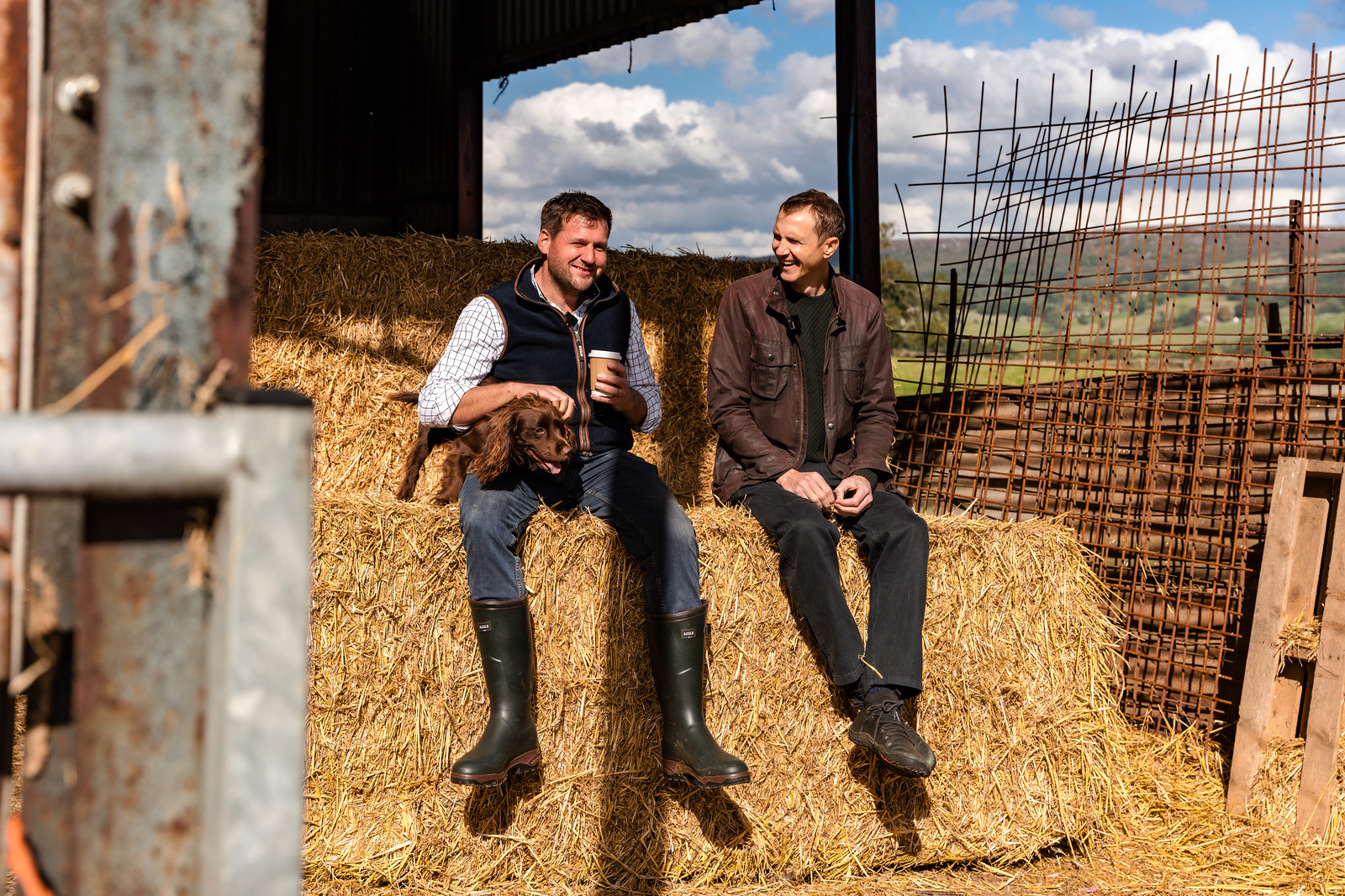 Founder Huw meeting a farmer and his dog, sitting on a hay bale