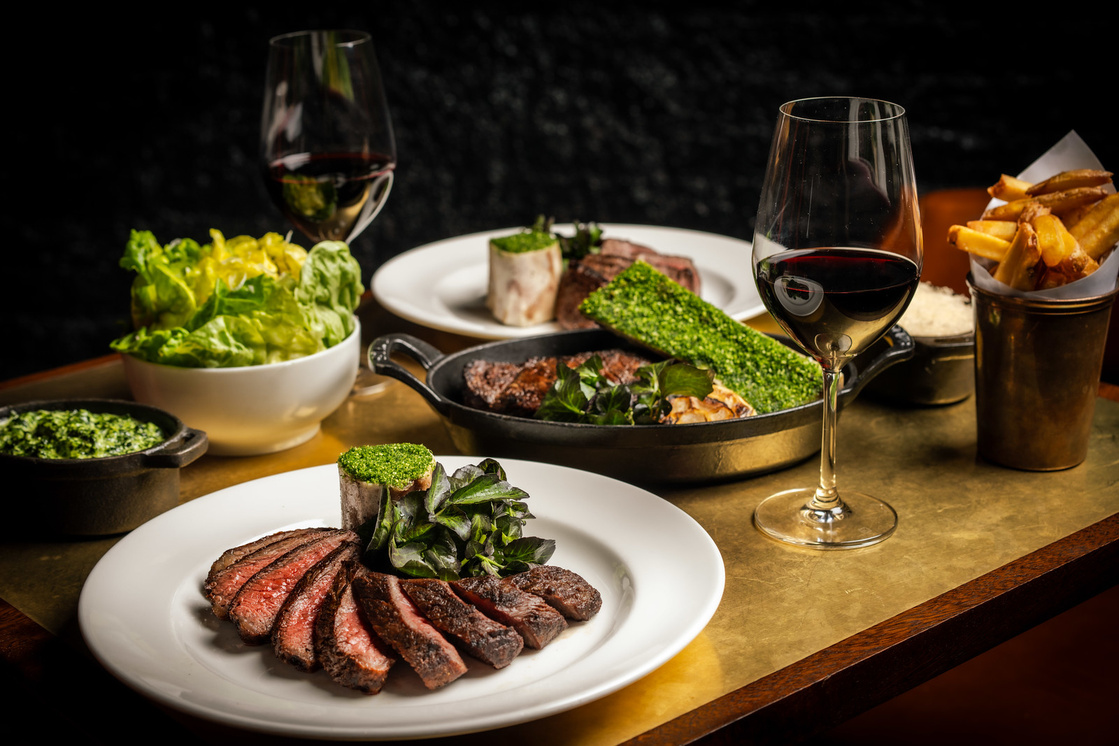 A golden finish table laden with wagyu steak dishes, sides and wine