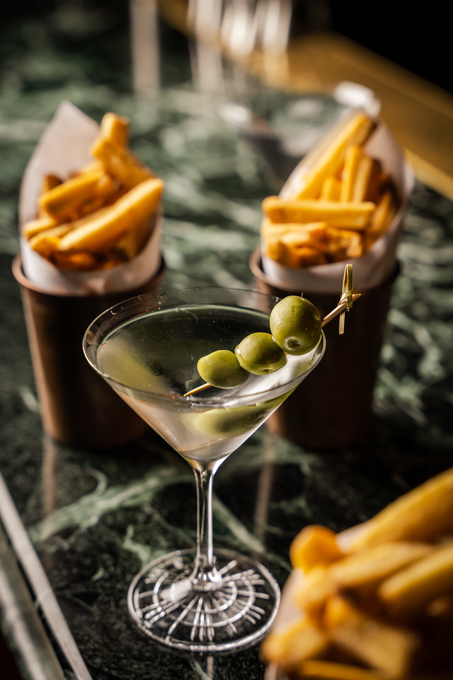 A close-up shot of a martinig, with pots of beef-dripping fries in the background and foreground