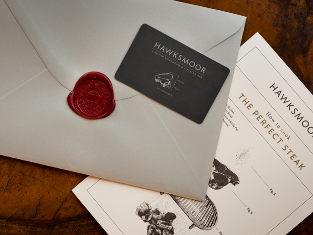 A gift card on a white envelope with a maroon wax seal, with a Hawksmoor menu in the background