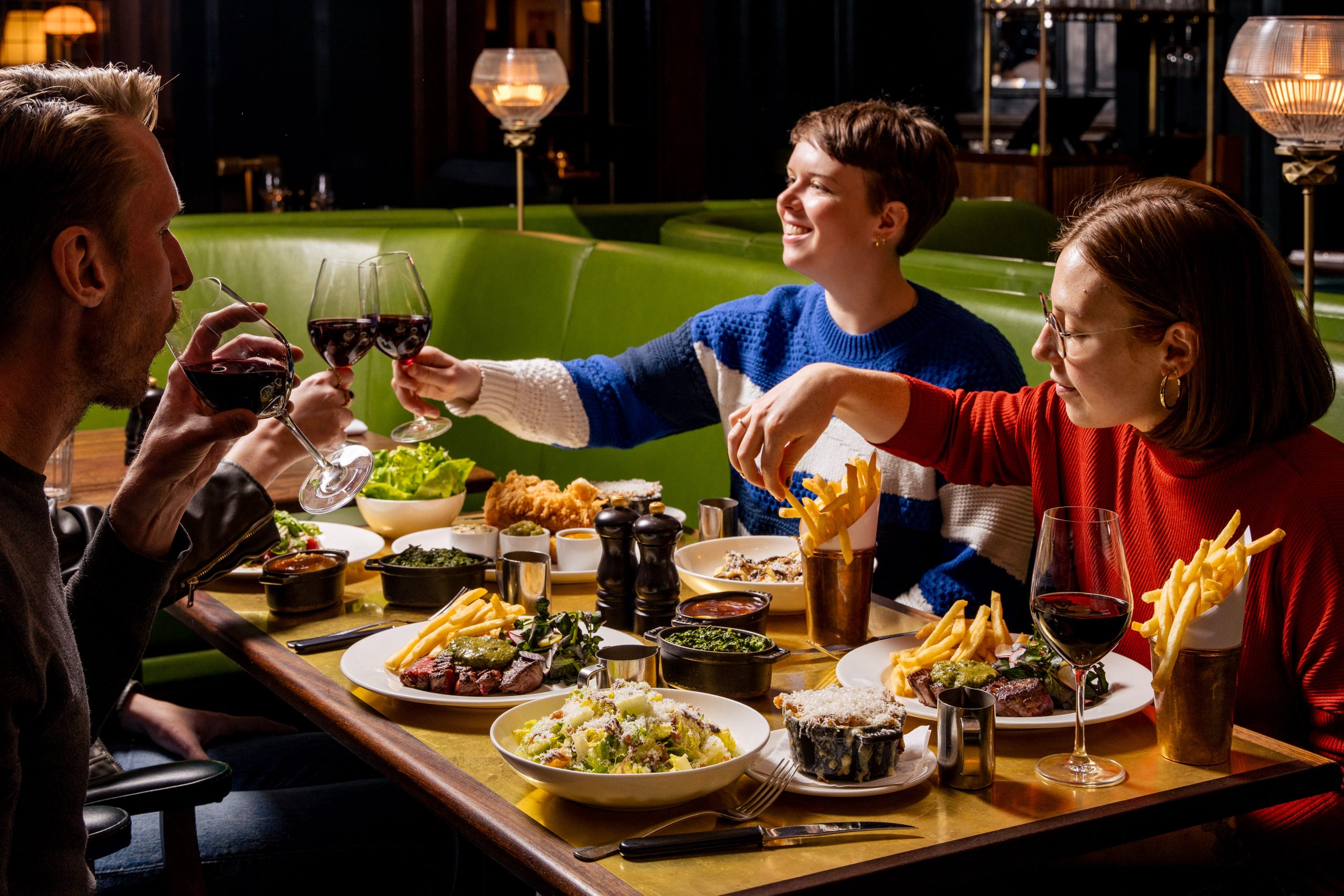 A group of friends around the dining table raising a glass over a spread of food