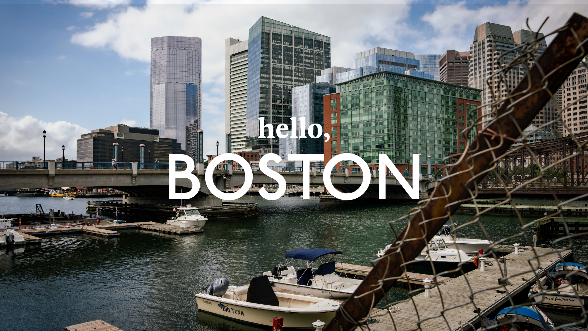 A wide angle shot of Boston Harbour with the text 'Hello, Boston' overlaid
