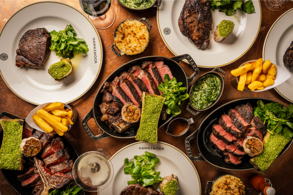 Variety of steaks in black skillets pictured from above on a wooden table, Hawksmoor Chicago