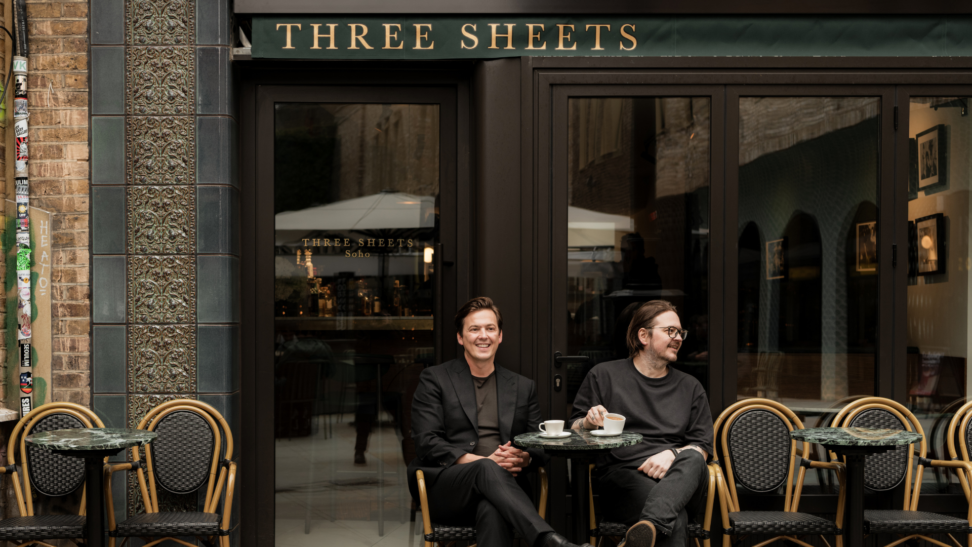 Two men sitting outside Three Sheets Bar