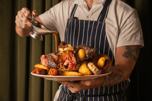 Ultimate Sunday Roast - chef pouring gravy over the generously laden platter of food