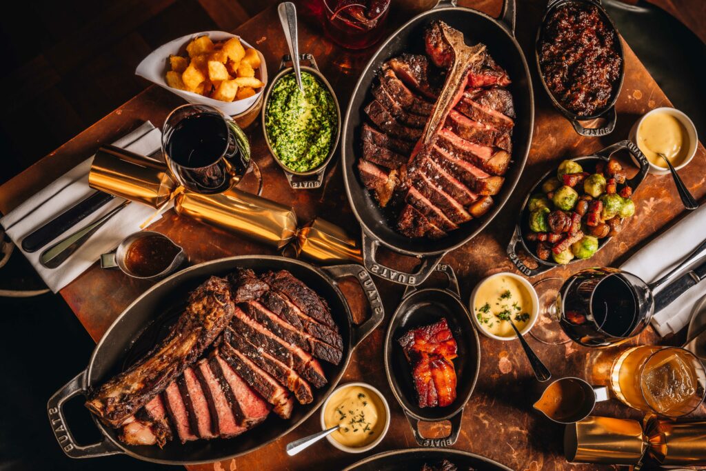 Christmas table at Hawksmoor - laden with steaks and festive sides