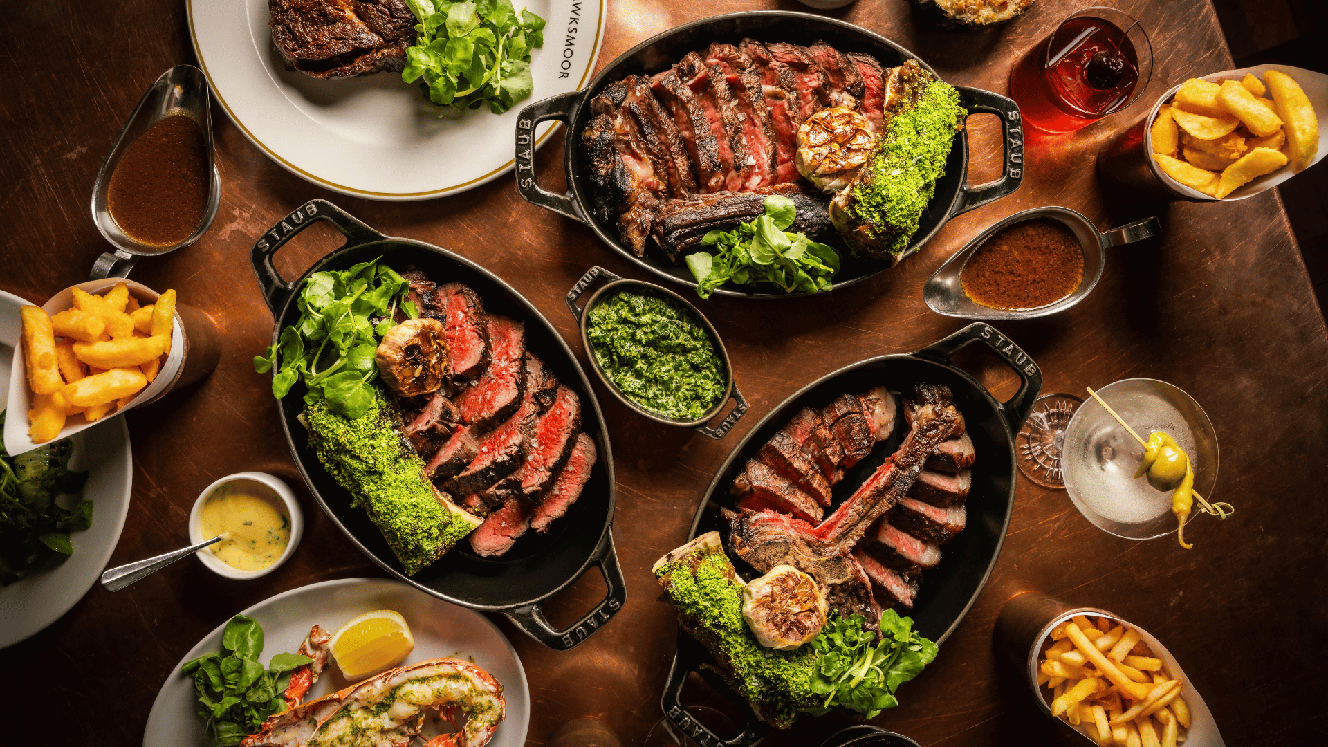 A table spread of sharing Longhorn steaks in skillets