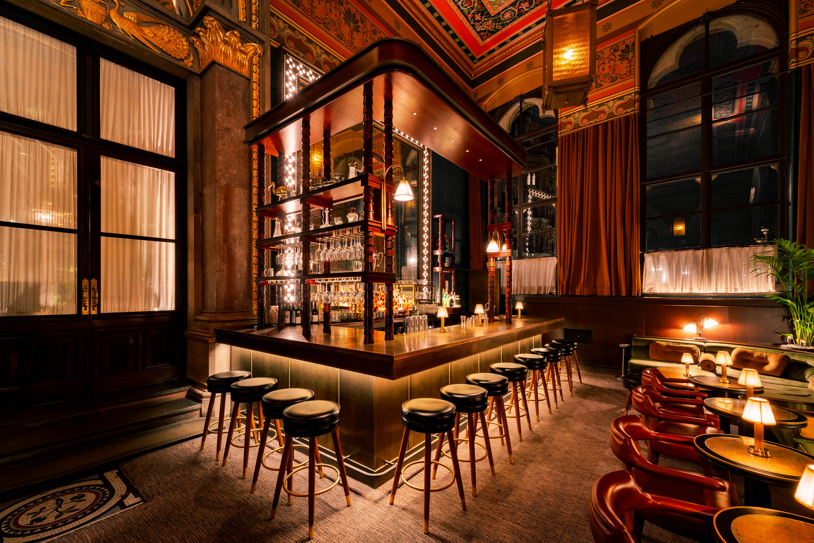 Seductively lit, opulent-looking bar surrounded by stools