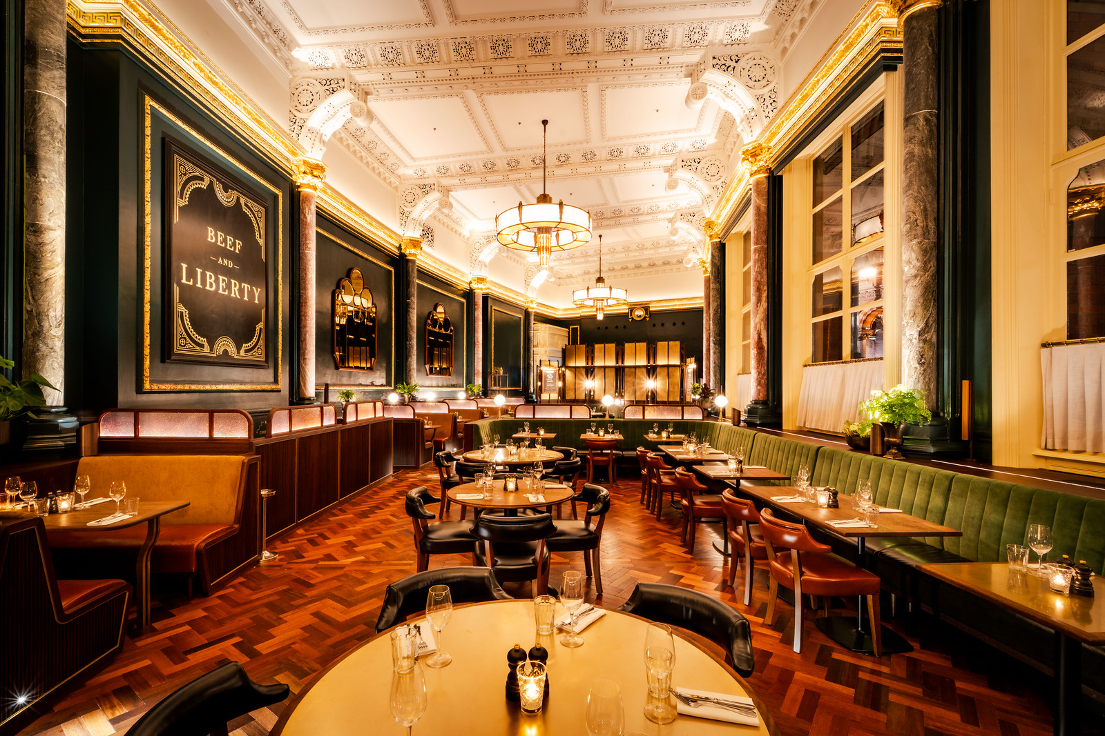 A shot of a beautiful, triple-height ceilinged restaurant dining room, with booths and tables