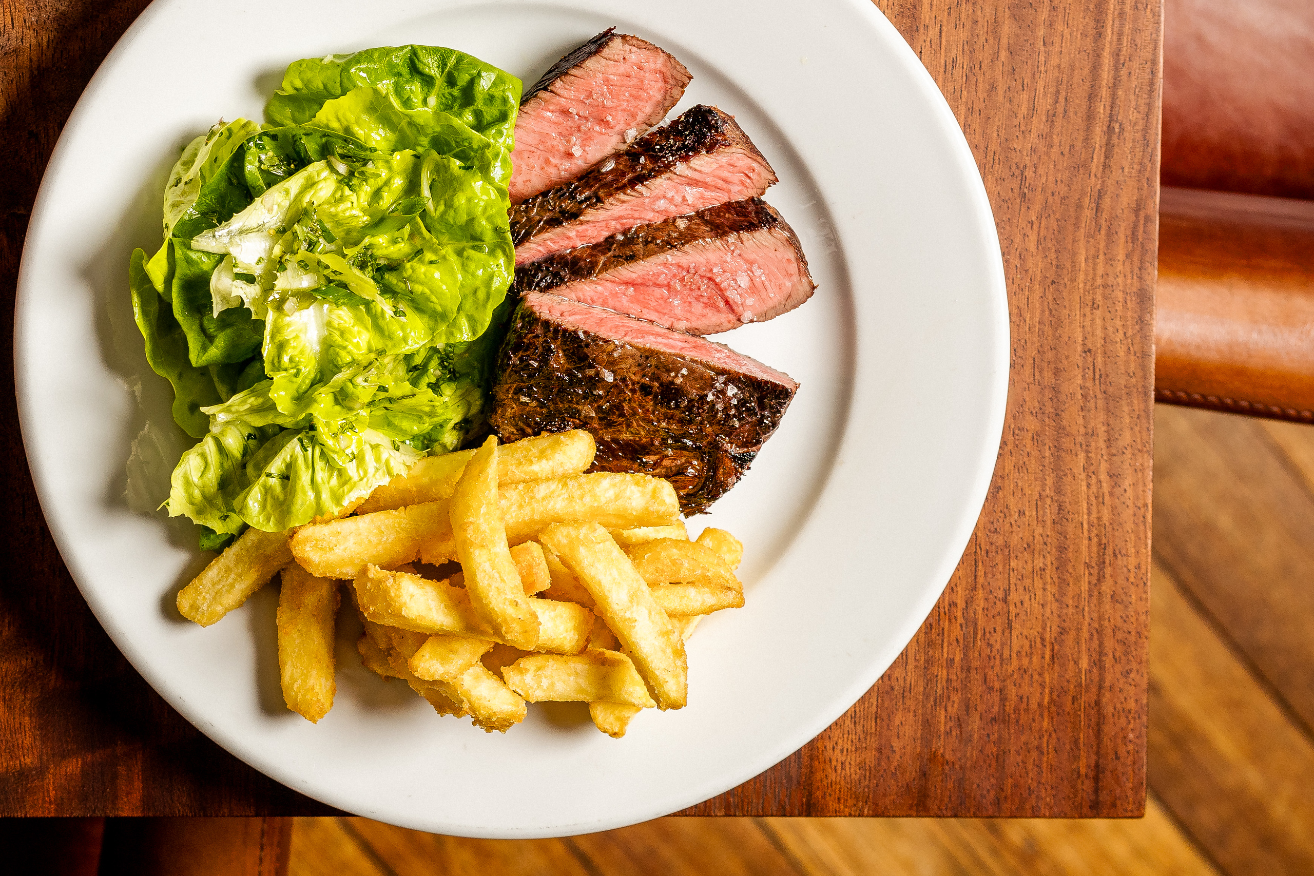 A plate of medium rare steak, chips and a salad.