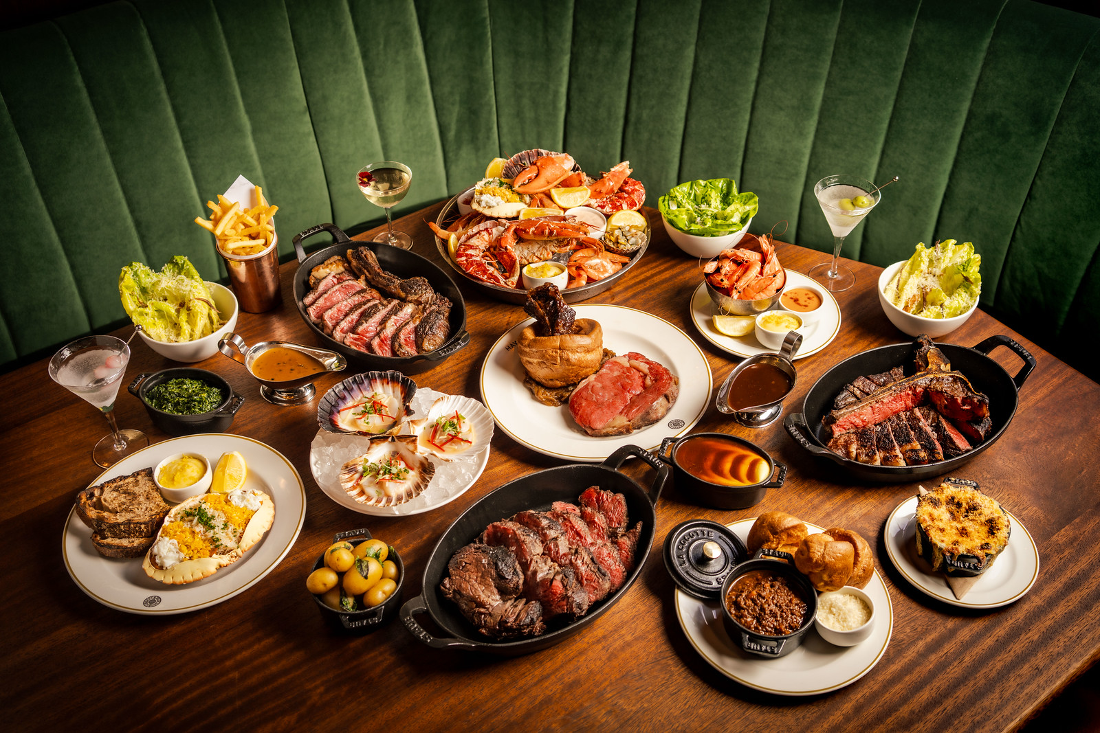 A wooden table laden with a variety of steaks, sides and starters