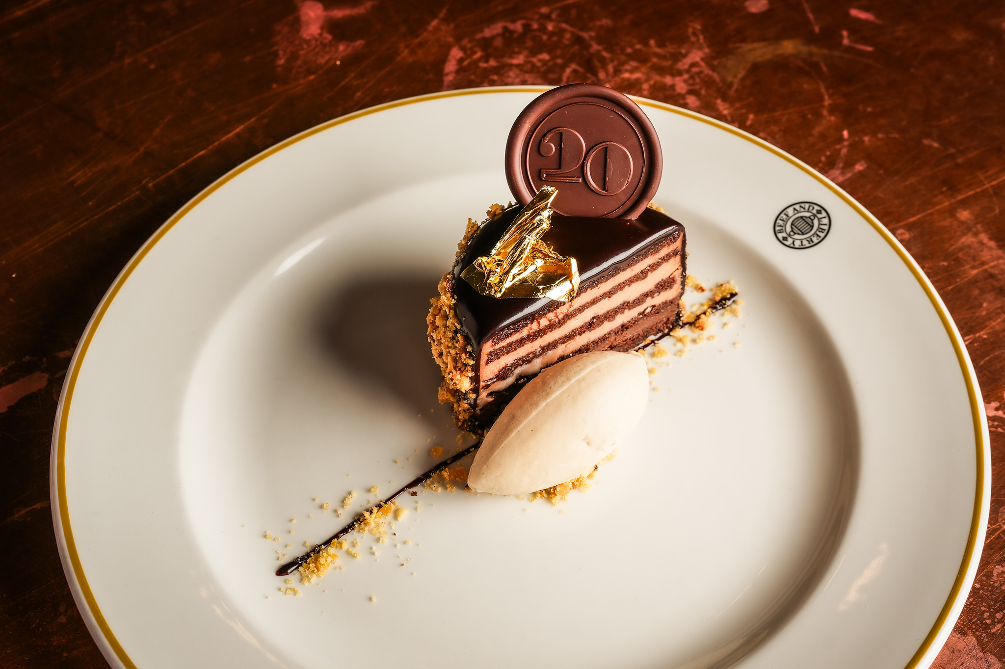 Hawksmoor birthday cake on a white plate, with a scoop on ice cream on the side