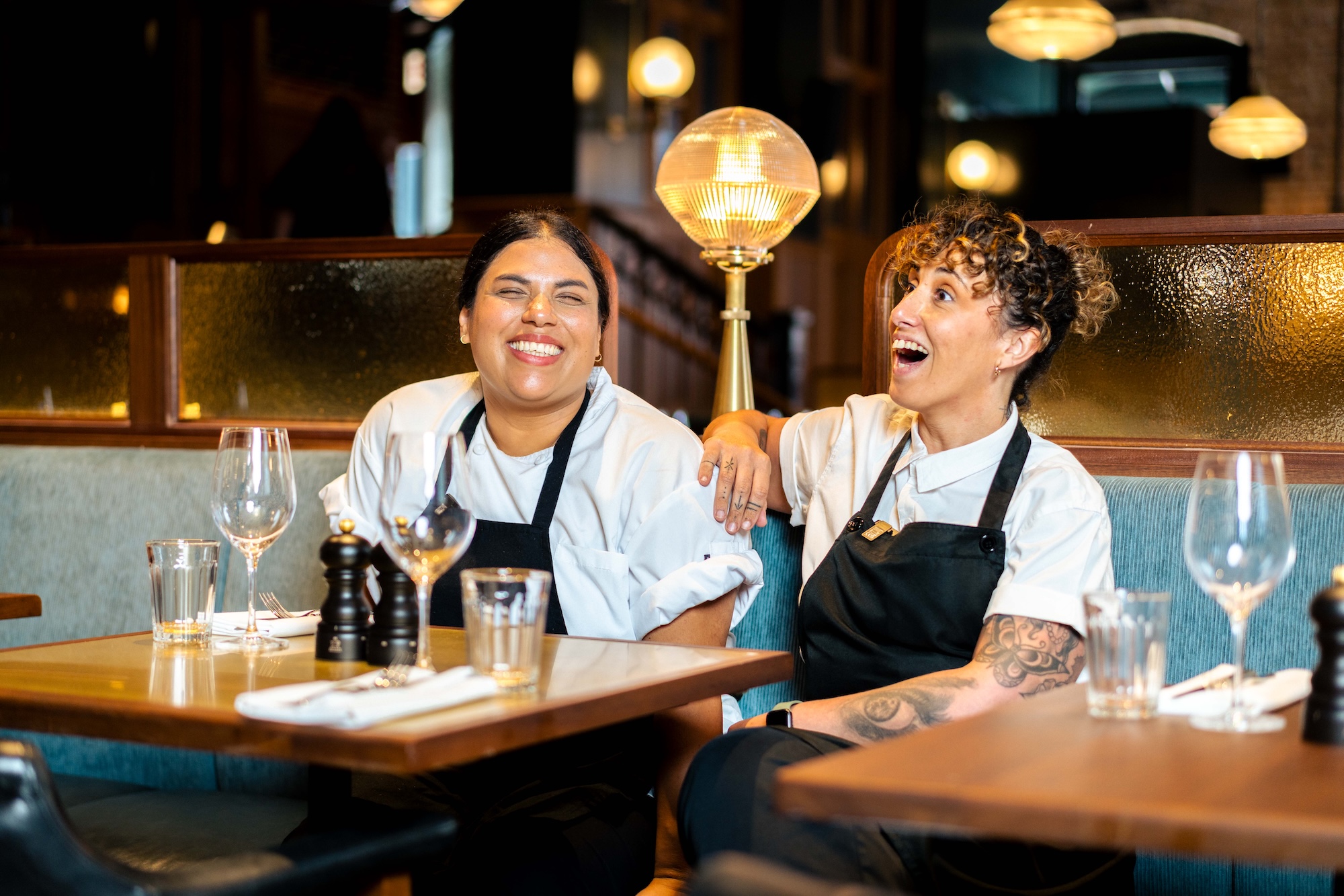 Two chefs sat at a resturant table laughing