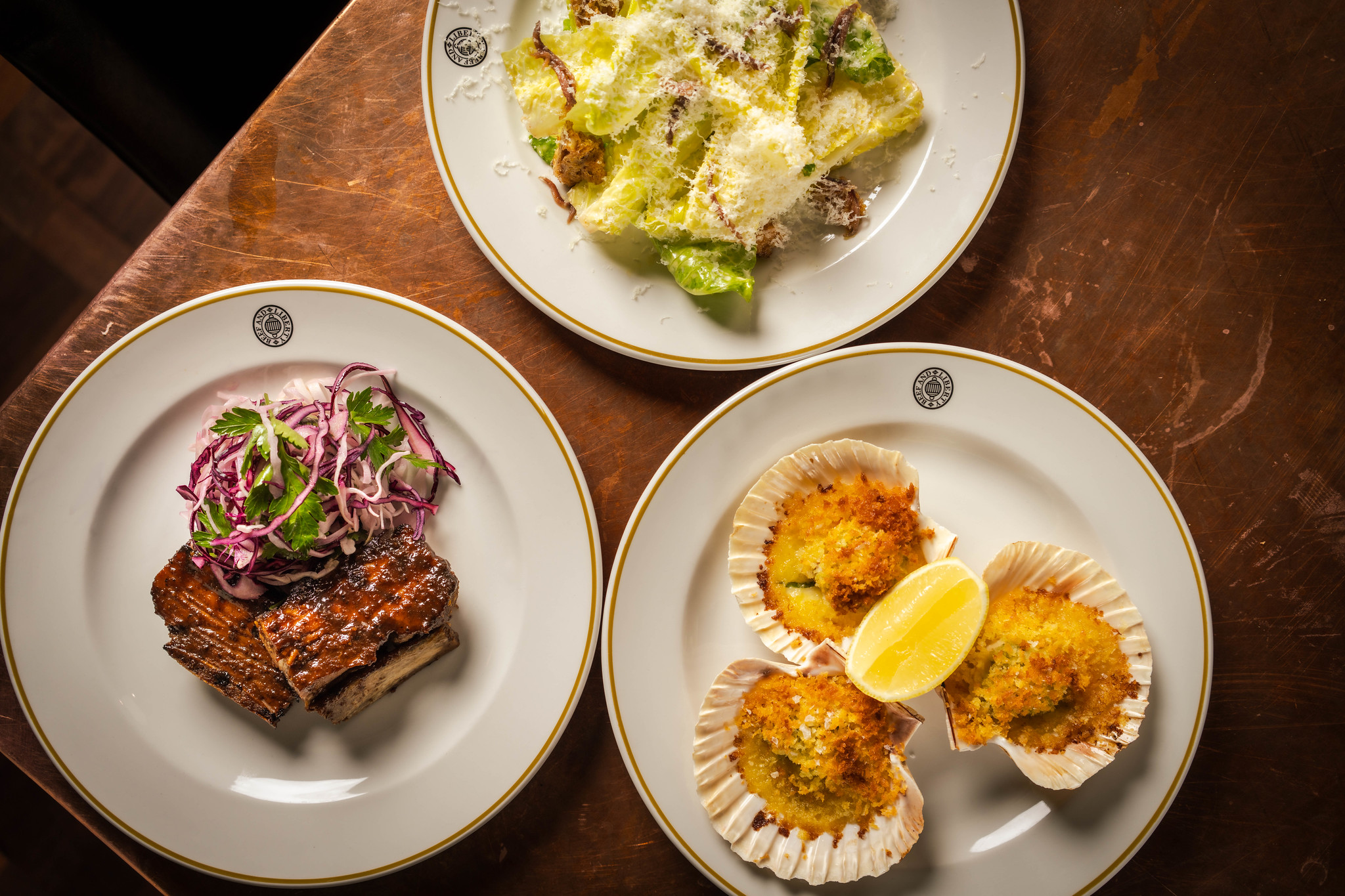 An overhead shot featuring 3 classic starters - ribs, scallops and Caesar salad