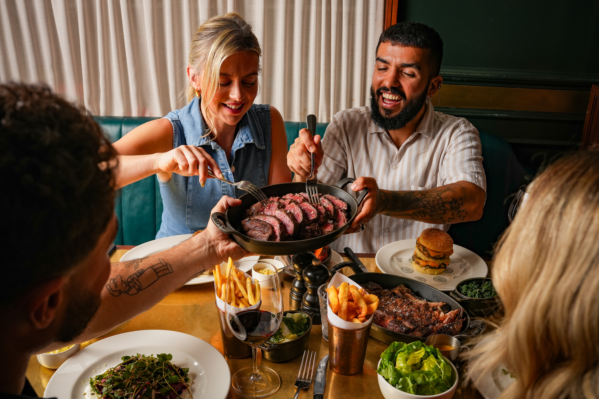 Liverpool 3 A group pf 4 friends arounf the table, with a skillet being held up and slices of sharing steak being picked up