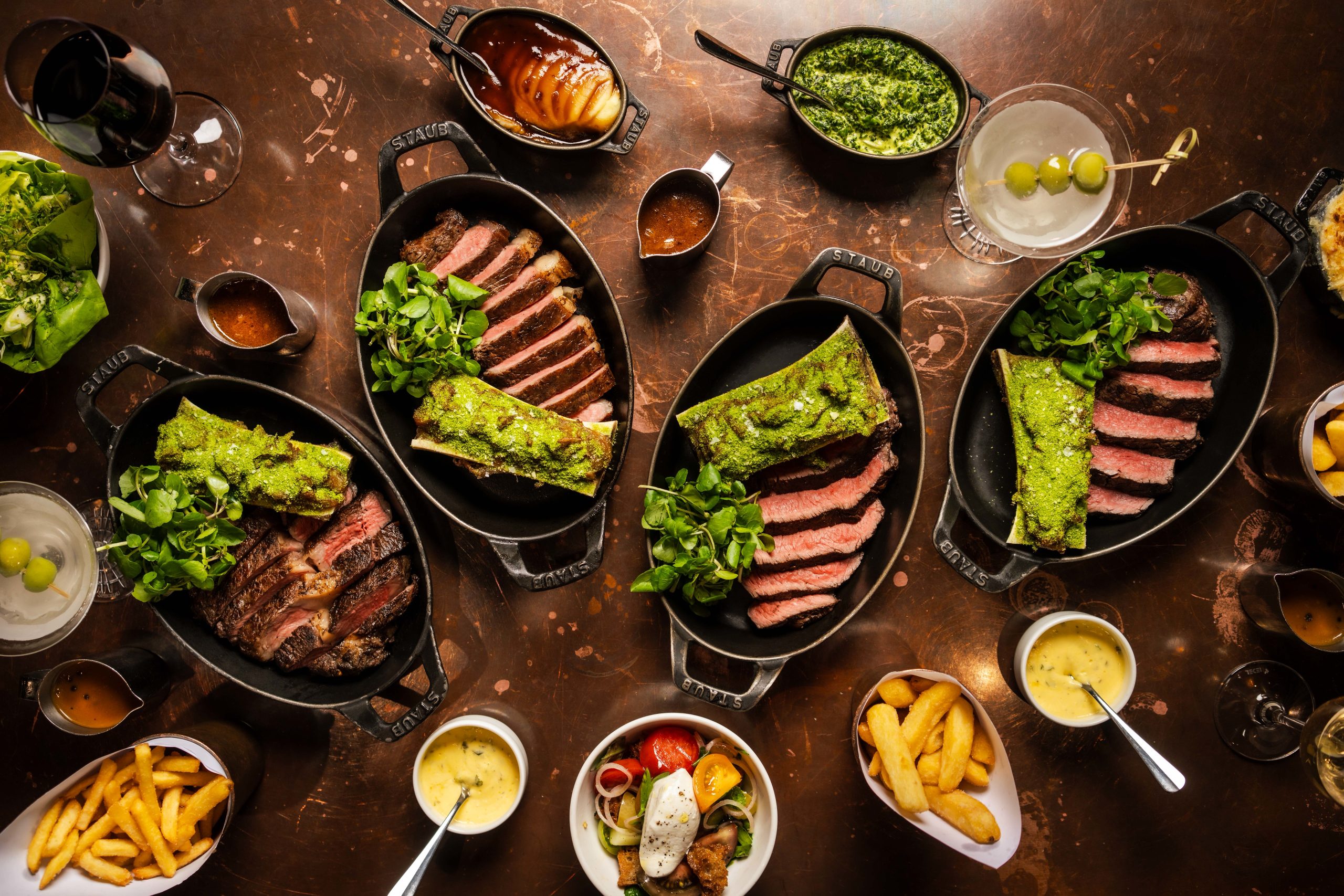 A Hawksmoor steak flight: fillet, sirloin, rump and ribeye served sliced in cast iron dishes with chips, sauces and salad