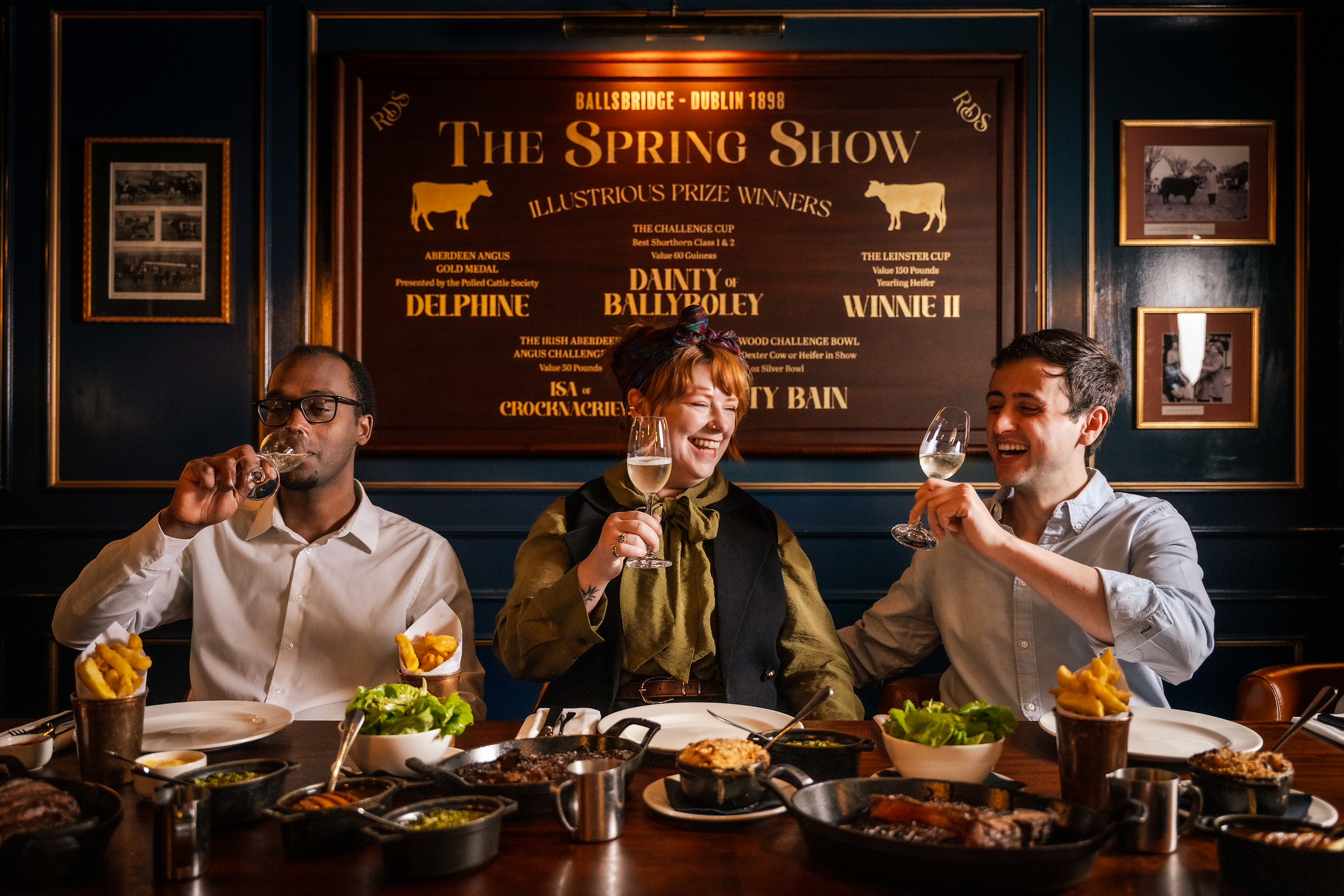 Three guests raising wine glasses over a shared table in a private dining room at Hawksmoor