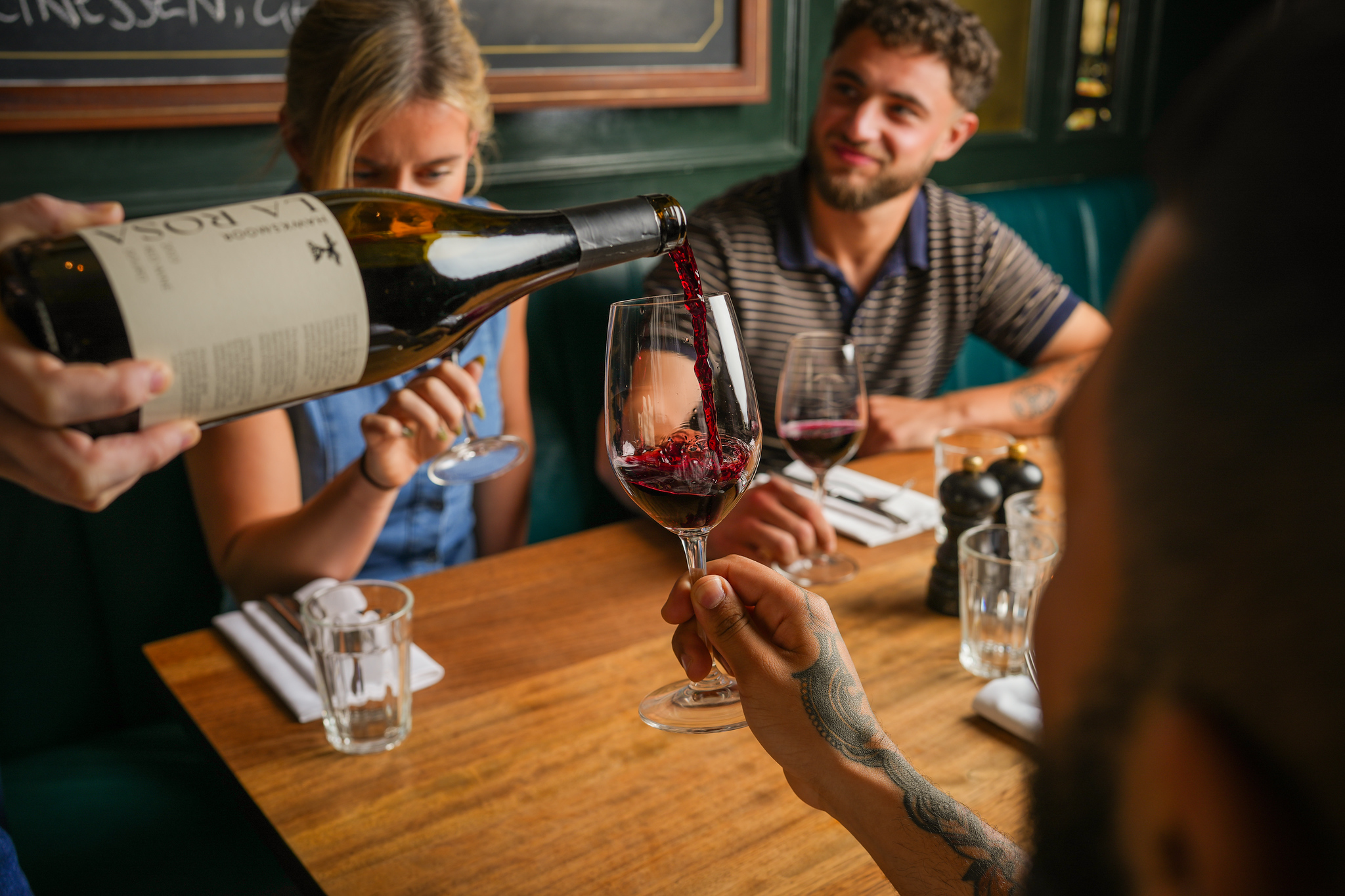 Red wine being poured from a large bottle into a guest's glass at a Hawksmoor table